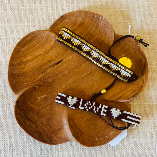 'LOVE' Seed bead Bracelet in Burgundy and White shown (lower position) with another bead design bracelet (upper position) on an olive wood trinket tray.
