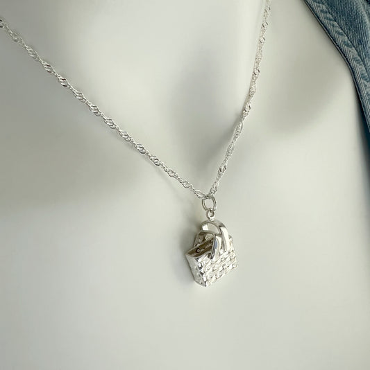 A sterling silver basket-shape charm necklace with a movable handle part, displayed on a mannequin. The chain is twist-style and adjustable.